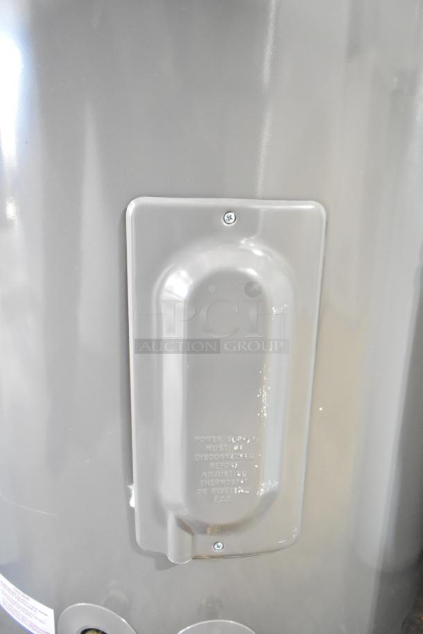 Rheem RSB565E Hot Water Heater, gray exterior, visible panel with embossed instructions. Good condition.