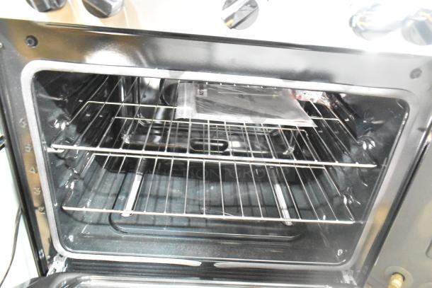 Frigidaire FCRG3052BSF range oven interior, featuring dual chrome racks. Visible control knobs suggest clean condition.