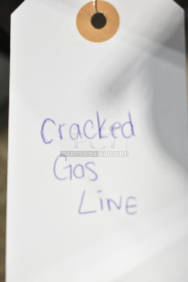 Frigidaire FCRG3052BSF 4-burner gas range with oven, noted for cracked gas line, white tag with issue description.