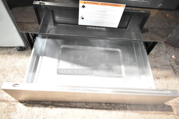 Frigidaire FCRG3052BSF natural gas range, 4 burners, with oven. Open storage drawer shown, includes safety warning label.