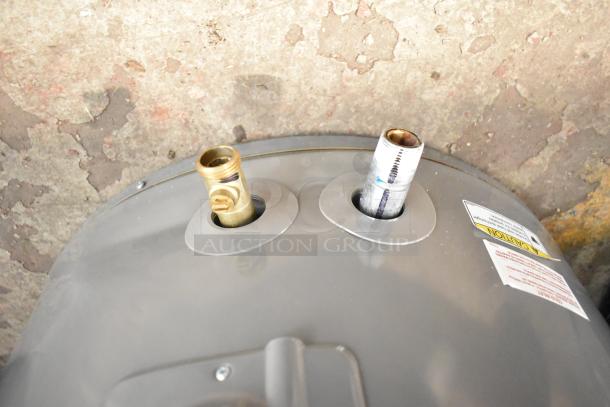Rheem hot water heater with brass and steel connections visible, caution label present, in used condition.