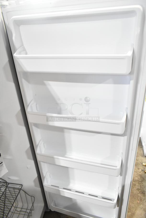 Brand new Frigidaire FFFU13F2VW upright freezer, door interior with four shelves, minor scratches, 115V, 1 phase.