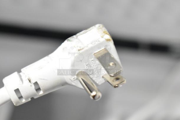 Close-up of a power plug belonging to a Magic Chef chest freezer, model HMCF5W4, with visible scratches and minor dents.