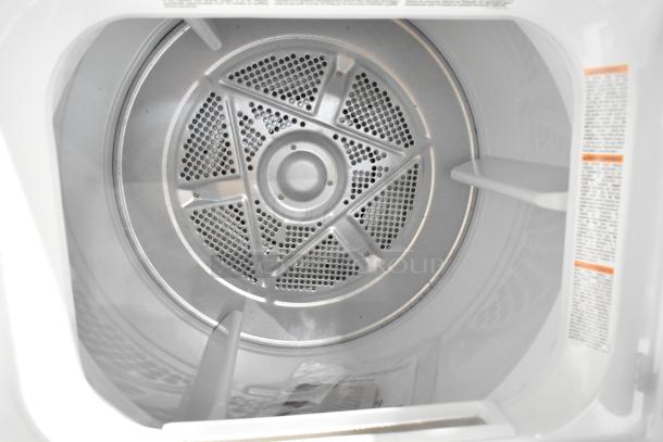 Frigidaire dryer drum interior, brand new with minor scratches. Visible safety labels and stainless steel perforated drum.