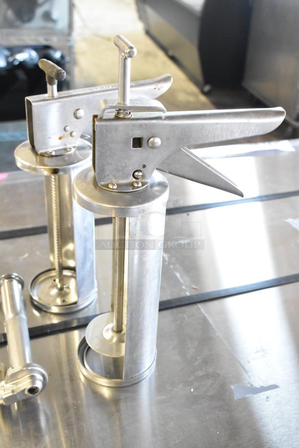 Silver metal caulk guns and pump piece set, showing industrial-grade build on metal surface, in good condition.