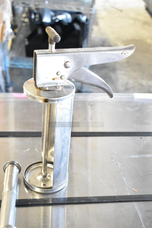 Metal caulk gun with trigger handle, visible rust spots. Auction lot includes five items. Sturdy condition.