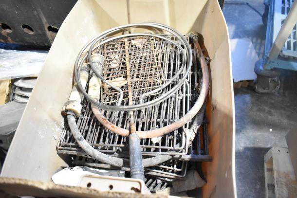 Assortment of various items in a bin, including metal parts, wires, and racks, showing signs of wear.