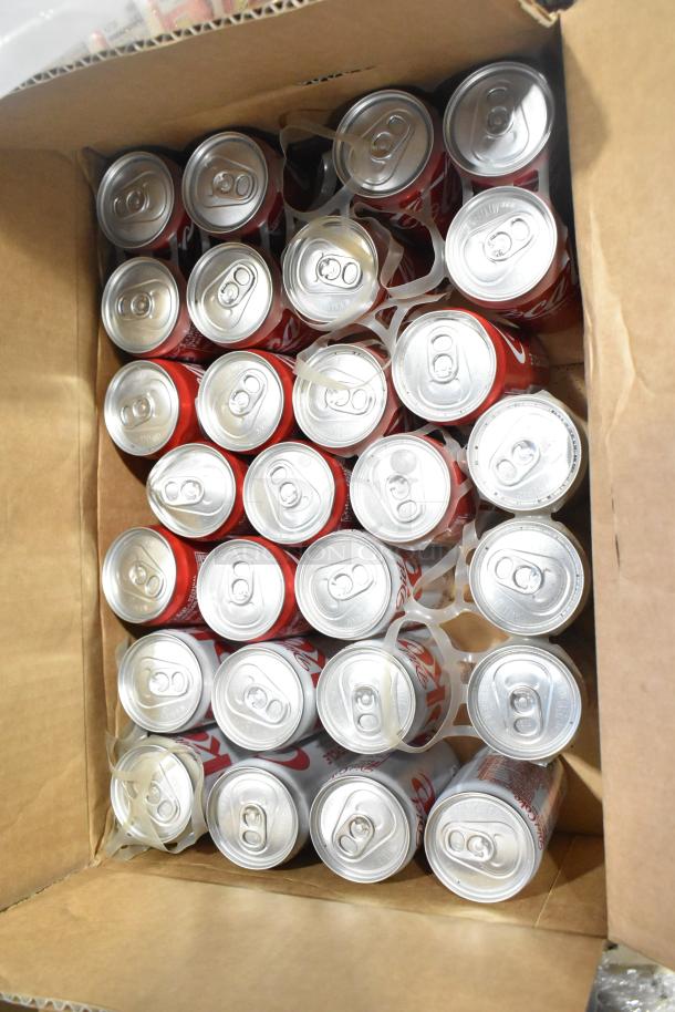 Box of 30 Coca-Cola cans in a cardboard container, arranged in rows. Cans appear unopened and in good condition.