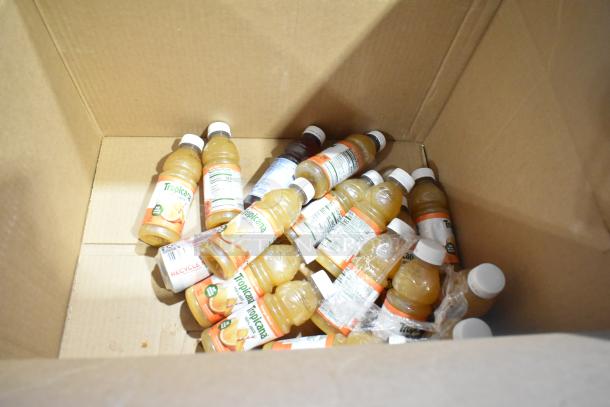 Cardboard box with assorted items including Tropicana juice bottles, indicating a bulk auction lot.
