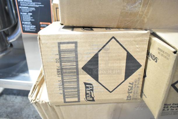 Cardboard boxes labeled "PURELL," containing new scratch and dent items like Pacific Blue dispensers, Rubbermaid refills, and Diversey cleaner.