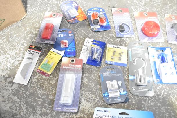 Assorted new scratch and dent items including bulbs, lamps, utility knife blades, and grommets in original packaging.