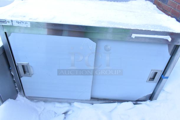 Steelton 522EBTB3048D work table, new with scratches, features two sliding doors and an undershelf. Tags indicate model and quantity.