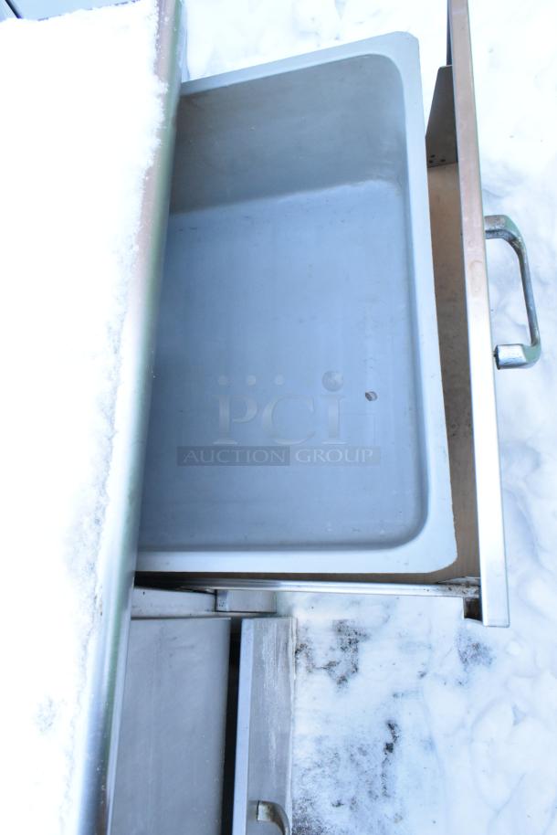 Stainless steel work table with four drawers and backsplash, shown with open drawer, in fair condition.