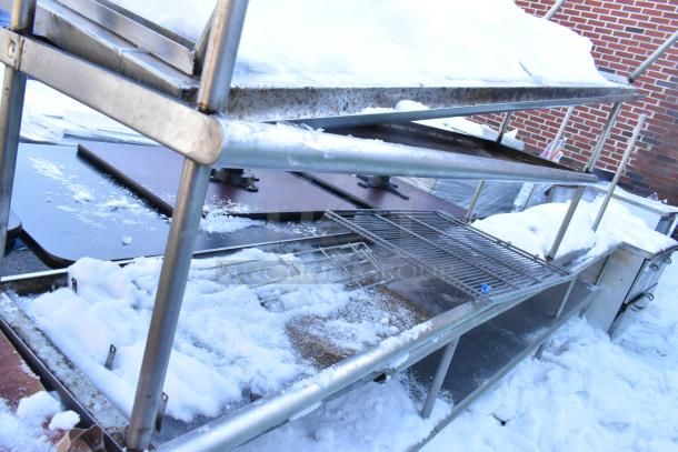 Four metal over shelves with snow, showing signs of rust and wear. Multiple tiers, suitable for storage.