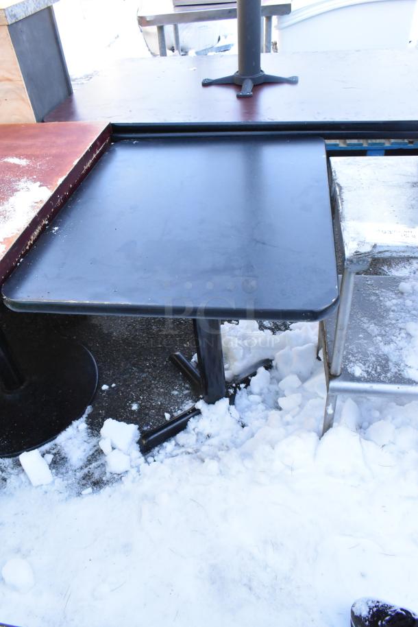 Three dining height tables with metal bases, outdoor setting, slight wear visible, snow around bases, auction lot.