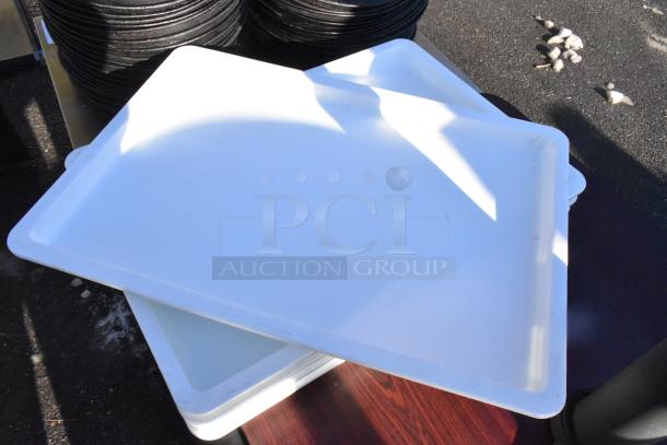 Table with an under shelf holding metal round baking pans, condition appears used, includes white trays on the surface.