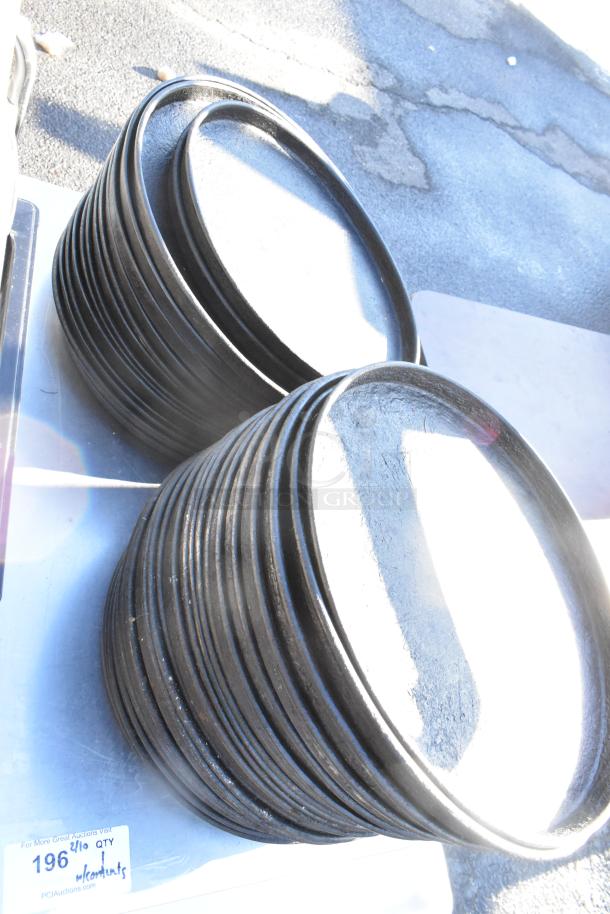 Stacks of metal round baking pans on a table with an under shelf, visible auction tag labeled "196, lot w/contents."