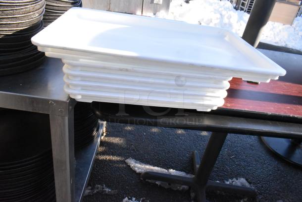 Stainless steel table with under shelf, holding several metal round baking pans and stacked white trays.