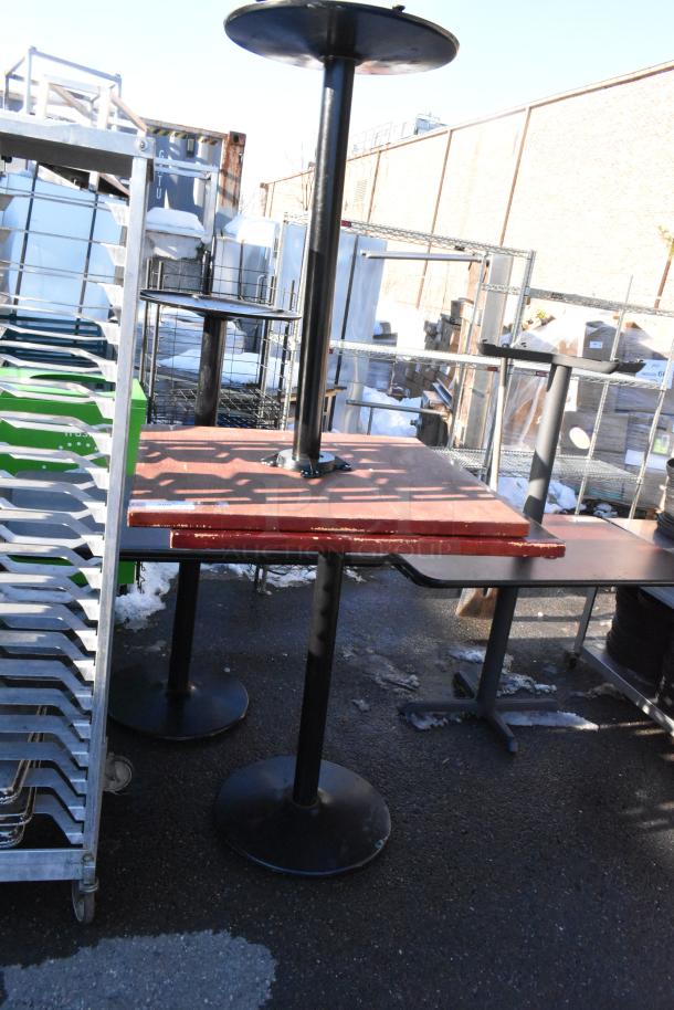 Two bar height tables with black metal bases and wooden tops, showing signs of wear. Ideal for commercial use.