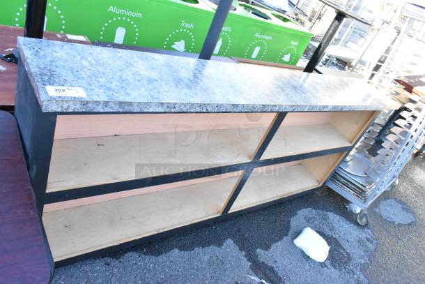 Gray granite countertop with wooden shelves, black frame. Used condition. Tag 202 affixed. Ideal for commercial use.