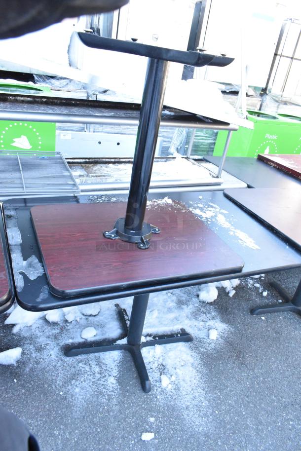 Six assorted dining tables with metal bases and wood tops, used condition, various finishes, shown outdoors on snow.