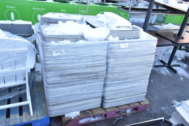 Stacks of 392 metal baking pans, full and half size, snow-covered, marked with lot numbers, ready for auction.