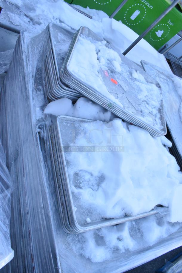 Stacks of full-size and half-size metal baking pans, covered in snow, indicating used condition. Total of 392 pans.