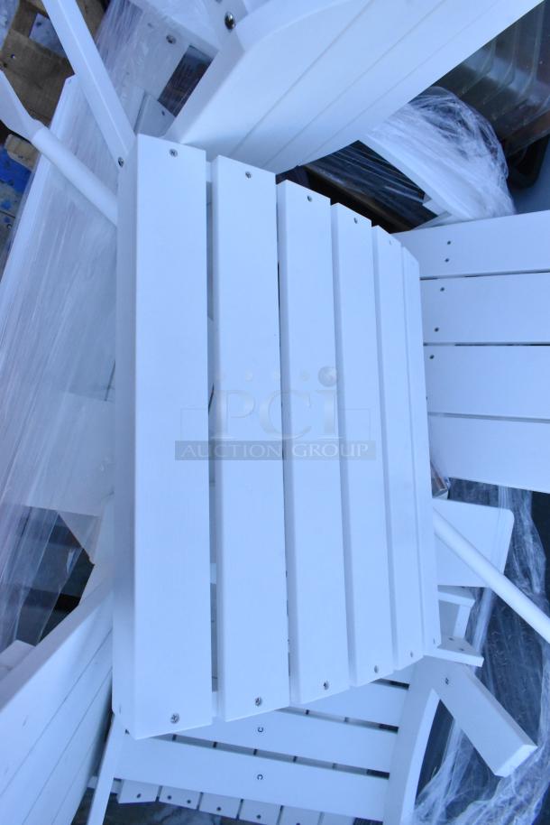 White wooden chairs stacked for auction, in new condition. Part of a lot including an end table and mixing paddles.