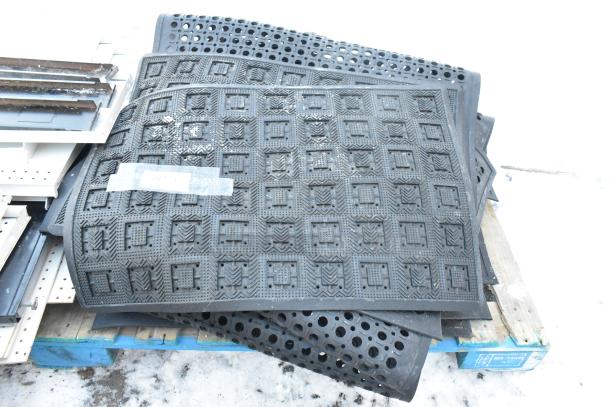 14 various floor mats with geometric patterns and perforations, stacked on a pallet. Some wear visible.