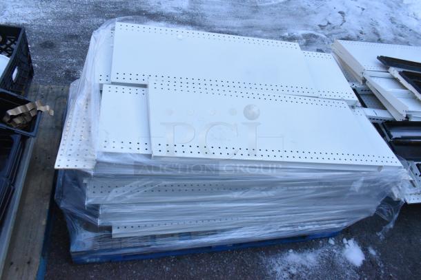 Pallet of assorted white metal shelves with perforated edges, wrapped in plastic, stacked on a blue pallet.