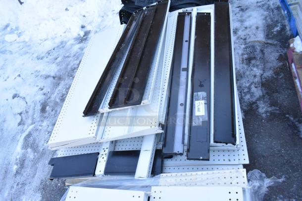 Pallet lot of various metal shelves, mixed colors, used condition, showing wear; some items with attached labels.