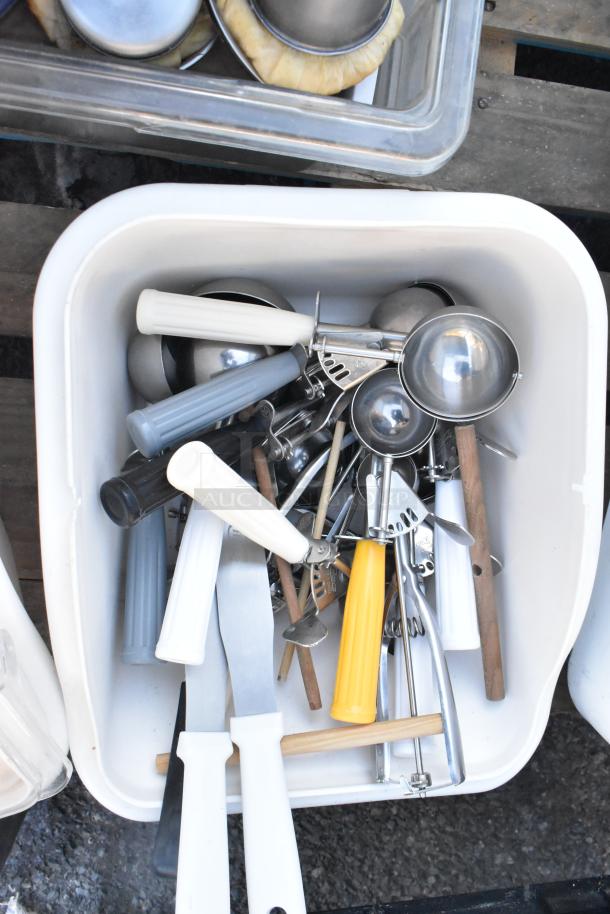 Pallet lot with ingredient bin filled with various kitchen tools, including serving spoons, spatulas, and scoops, in good condition.