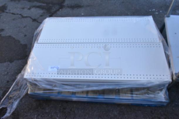 Pallet lot of perforated white shelves, wrapped in plastic, in good condition with a visible tag indicating lot number.