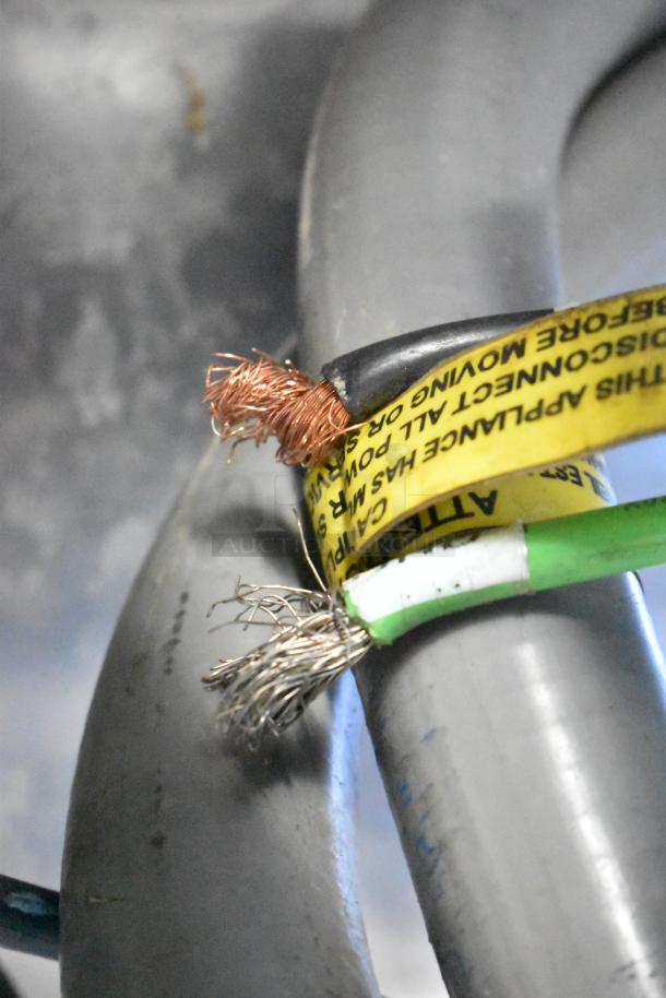 Close-up of exposed wires in a commercial oven. Yellow label advises caution when disconnecting power. Mono FG180C-UZ52 model.