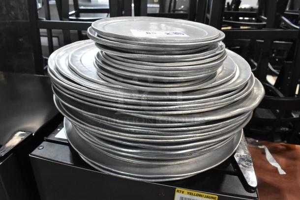 Stack of round metal baking sheets, used, showing light wear. Auction label visible. Total of 51 pieces.