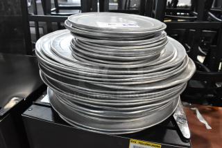 Stack of round metal baking sheets, used, showing light wear. Auction label visible. Total of 51 pieces.