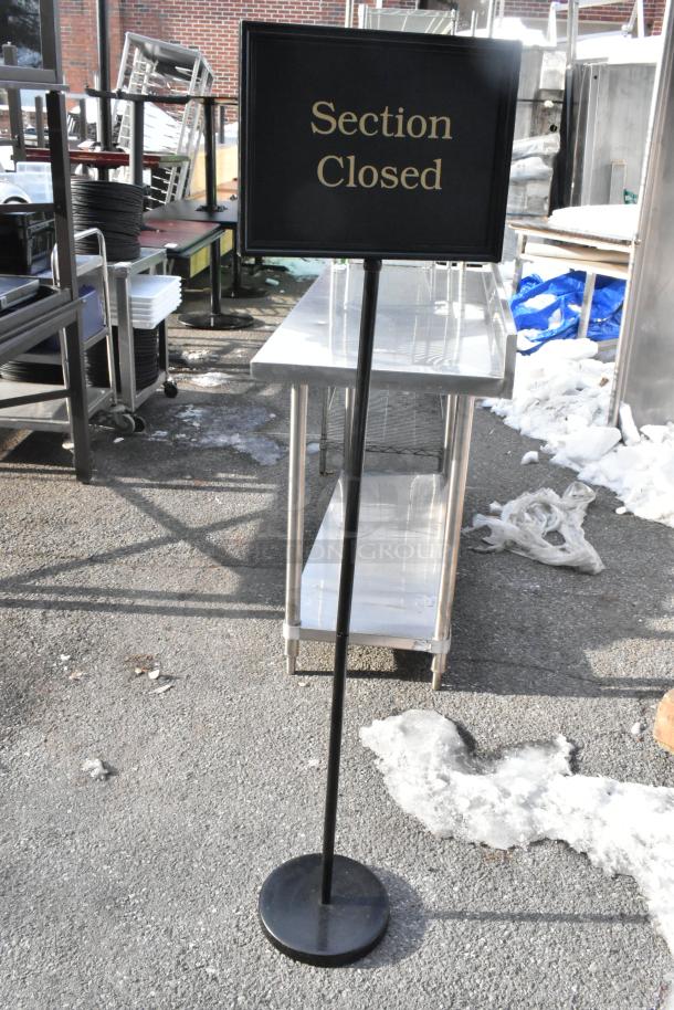 Black "Section Closed" sign on stand; outdoor setting; sturdy metal base; good condition.