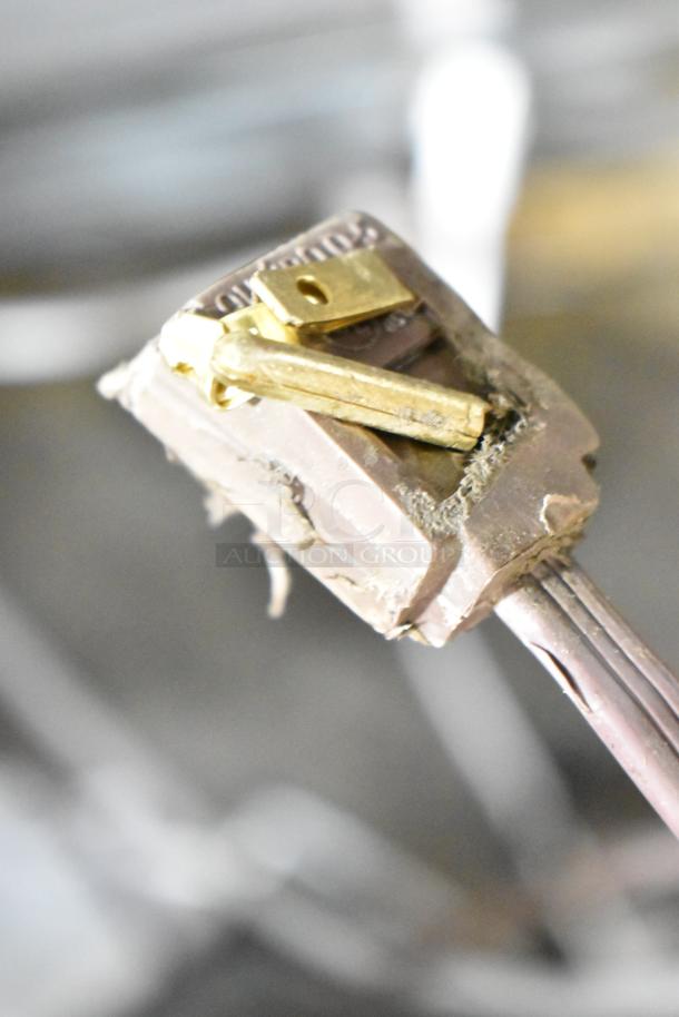 Close-up of a worn electrical plug with exposed wires and visible grime, indicating wear and tear.