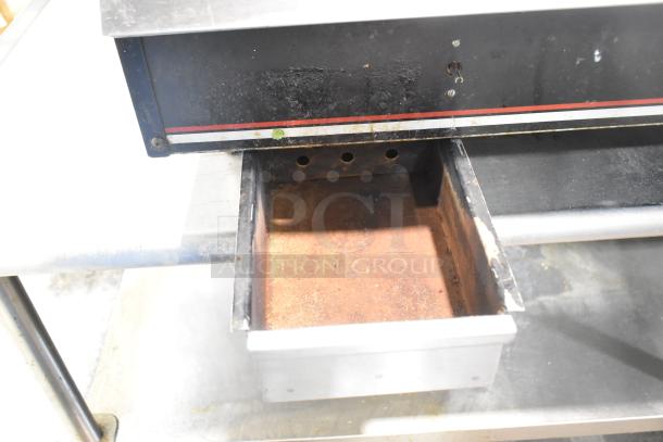 Wolf Regency countertop flat top griddle on equipment stand with commercial casters, showing pull-out grease tray.