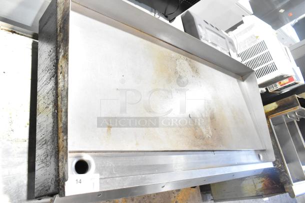 Wolf Regency Commercial Griddle with thermostatic controls on equipment stand. Shows signs of use, on commercial casters.