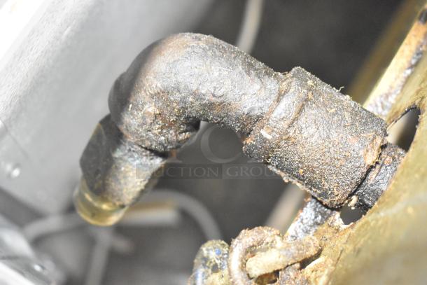 Close-up of a corroded metal pipe on a Wolf Regency Commercial Countertop Flat Top Griddle. Condition suggests wear.