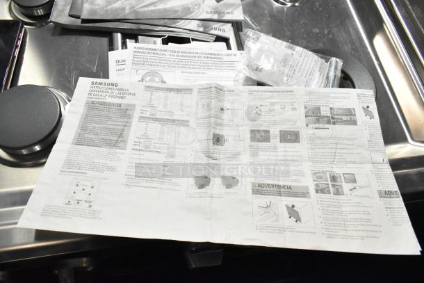 Brand new Samsung gas range, 4 burners, dual ovens, scratch and dent condition, missing grates, includes manuals.