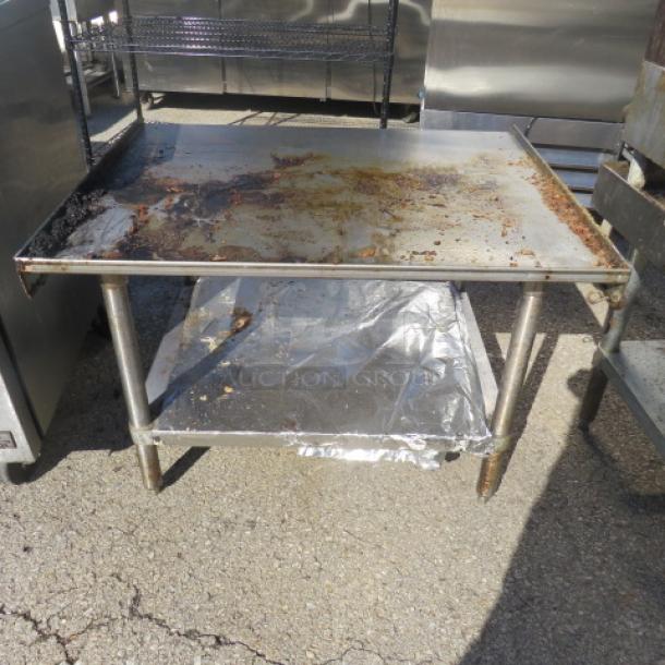Regency stainless steel equipment table with under shelf, model 600FS3024G. Measures 24x30x25.5 inches. Used condition, visible rust.