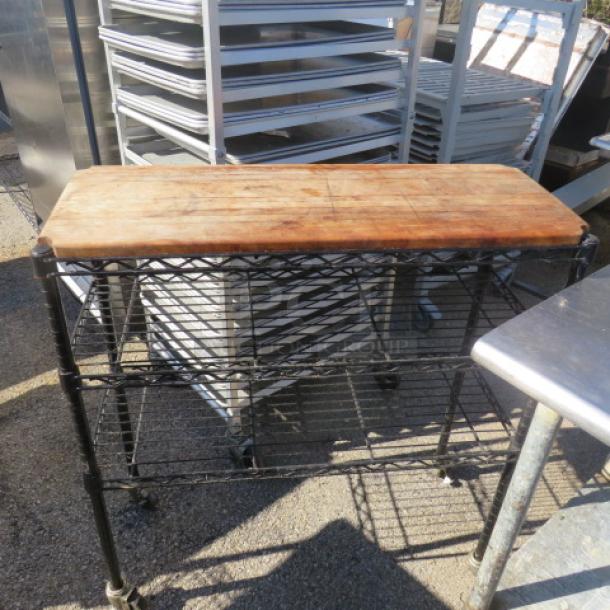 Metro shelf unit with three metal shelves, wooden top shelf, and casters. Dimensions: 36x14x38.5 inches.