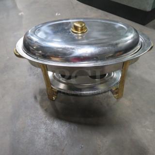 Stainless steel oval chafer with gold accents, includes a lid and sturdy frame, in good condition.