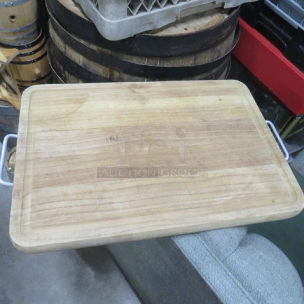 12x17 wooden cutting board with metal handles, slight wear on surface, ideal for kitchen use.