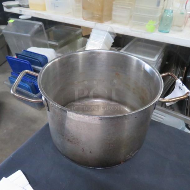 Stainless steel stock pot, 10x7 inches, with sturdy handles, some wear visible, ideal for cooking large quantities.