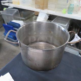 Stainless steel stock pot, 10x7 inches, with sturdy handles, some wear visible, ideal for cooking large quantities.