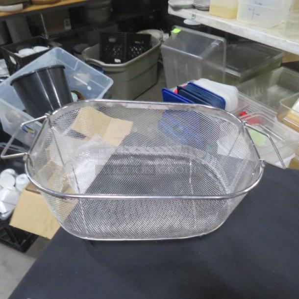 Stainless steel strainer with handles, rectangular mesh design, in good condition, placed on a black surface.