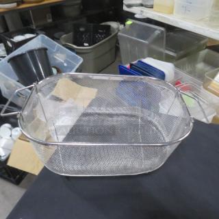 Stainless steel strainer with handles, rectangular mesh design, in good condition, placed on a black surface.